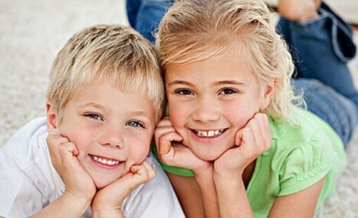 Portrait of siblings watching television on the floor in the living-room