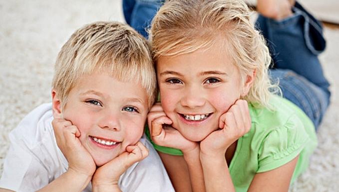 Portrait of siblings watching television on the floor in the living-room
