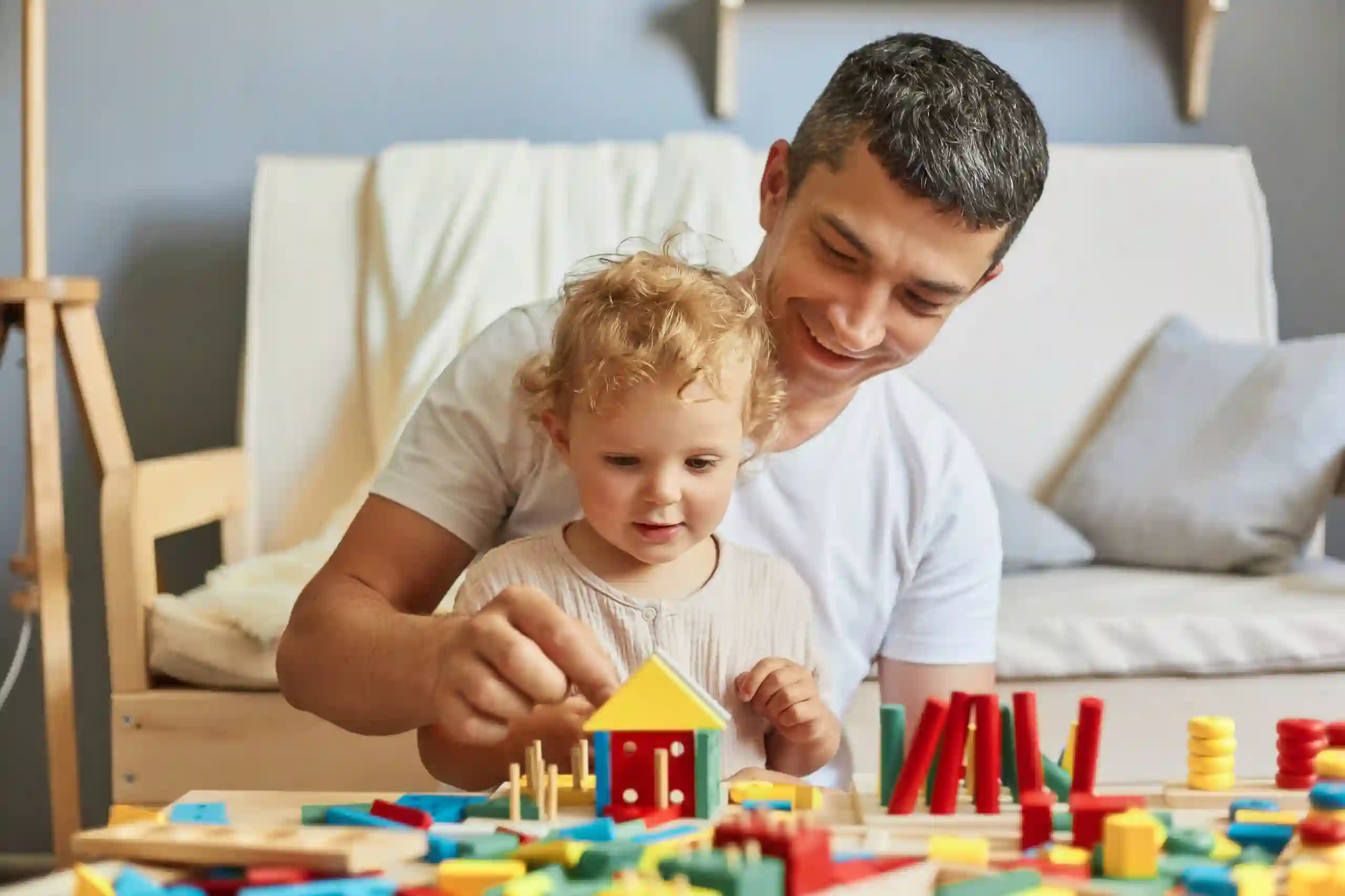 Baby girl playing sorter with her father in living-room, spending time together after napping, caring daddy, dad playing with his daughter using education toys.